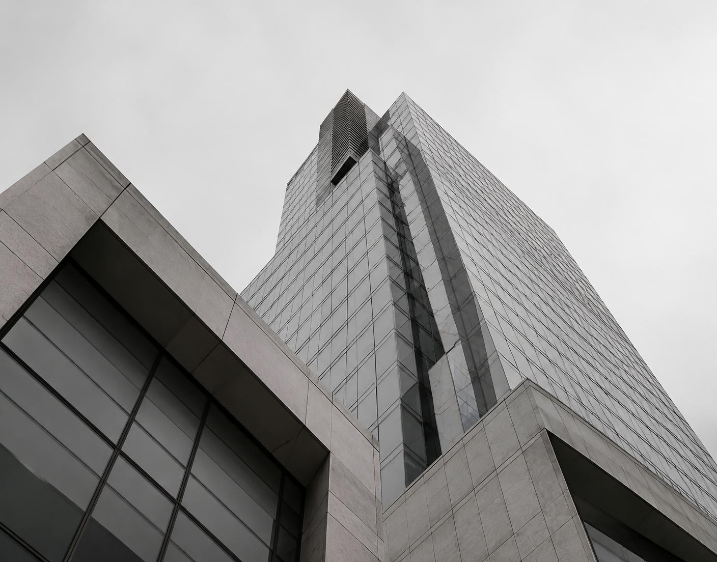 Looking up at modern glass and stone office towers